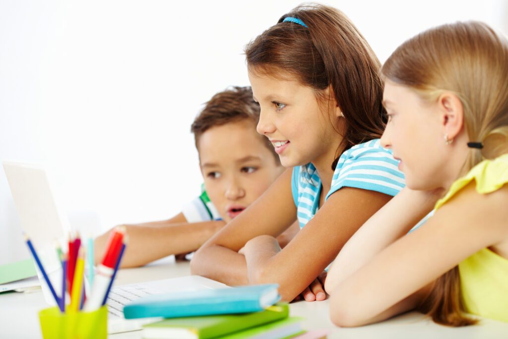 Un grupo de tres niños estudiando con un ordenador portátil.